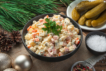 Wall Mural - Olivier salad in a black bowl on a dark background with Christmas decorations.