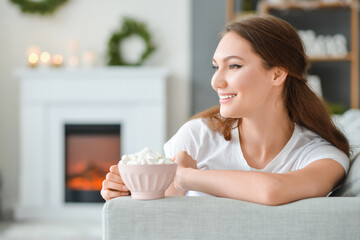 Sticker - Beautiful young woman with cup of hot cacao drink at home on Christmas eve