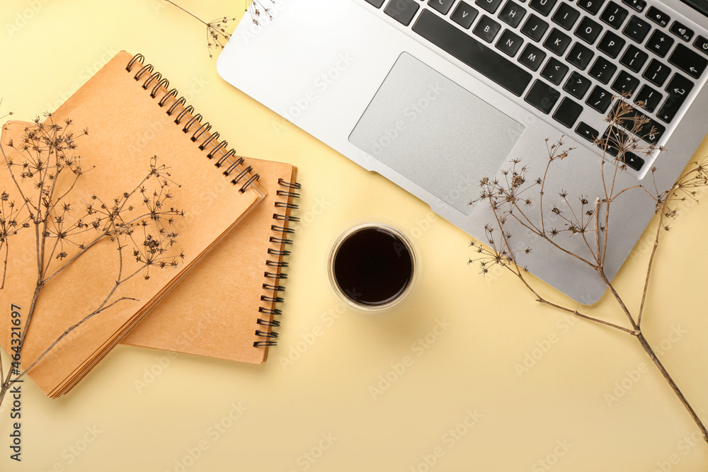 Composition with cup of coffee, laptop and notebooks on color background