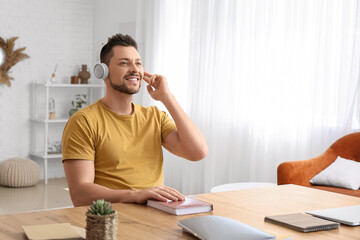 Canvas Print - Man with headphones listening to audiobook at table