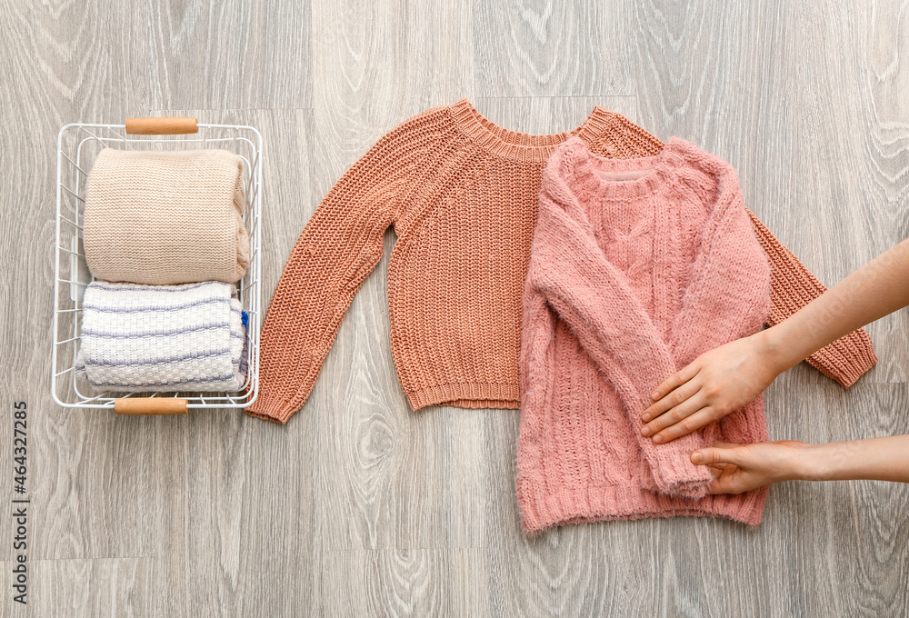 Woman folding clothes on grey wooden background