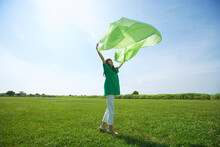 芝生の上で緑の布を仰ぐの緑の服の女性
