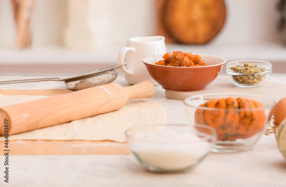 Raw dough and ingredients for preparing pumpkin strudel on table, closeup