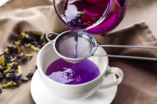 Pouring Of Butterfly Pea Flower Tea Into Cup On Table