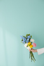 グリーンの壁前で花束を持つ女性の手