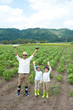 © amanaimages - 畑で収穫した野菜を持つ父と子供男女