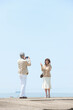 © amanaimages - 海のリゾートで写真を撮る旅行中の中年夫婦