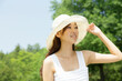 © amanaimages - 新緑の中の白い帽子をかぶった女性