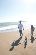 海辺で犬と散歩する父と息子