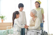 © amanaimages - 車椅子の老人と孫と介護ヘルパー