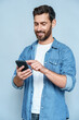 © Stock 4 You - Vertical portrait of handsome 30s 40s old businessman using telephone mobile cellphone. Mature smiling freelance man entrepreneur in casual outfit holding smartphone device isolated on blue background
