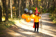 © Ольга Симонова - A girl in a witch costume and hat on a broom with orange and black balloons is playing in the autumn forest, going to a Halloween party