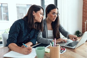 Two beautiful designer women working in a design project while choosing materials in the office.