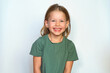 portrait of a happy child on a white background in a green t-shirt smiling. The little girl plays with her sly eyes. Happy girl. copy space. Childhood concept.