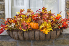 A Fall Themed Moss Lined Window Flower Box Filled With Orange, Red And  Yellow Leaves And Pumpkins