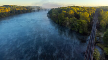 Mist Rising Off Catawba River In South Carolina, USA With Railroad Trestle And Early Fall Foliage