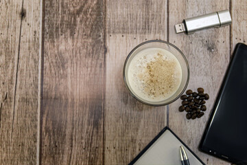 Poster - Top view of a glass of iced coffee, coffee beans, and other objects on a wooden table - copy space