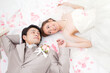 © amanaimages - 寝転ぶ新郎新婦と花びら