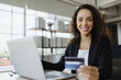 © anut21ng Stock - young woman holding credit card for shopping online with computer in office