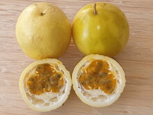 Two Whole Passion Fruits And One Cut In Half With Its Seeds.