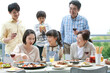 © amanaimages - テラスで食事する3世代家族