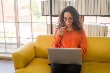 latin woman working with laptop on sofa