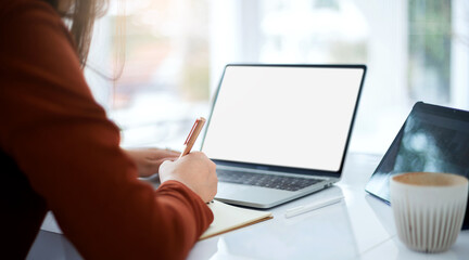 Wall Mural - Focus on hand young asian woman writing on book and using computer laptop and tablet working or study online