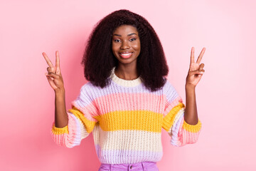 Poster - Photo of pretty cheerful dark skin girl two hands fingers show v-sign look camera isolated on pink color background