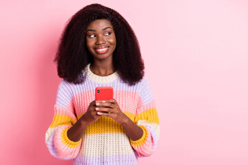 Poster - Portrait of positive dark skin blogger look empty space hold phone toothy smile isolated on pink color background