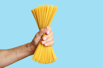 Spaghetti pasta in hand on a blank background. Raw Italian spaghetti before cooking and eating Italian food