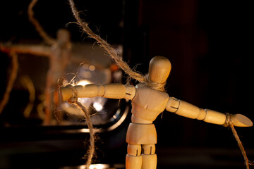 a wooden man on ropes tied to a man's hand, manipulation of people and slavery, free will, power