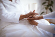 © Wavebreak Media - African american female doctor holding hands of senior female patient at home