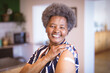 © Wavebreak Media - Portrait of smiling senior african american woman showing bandage on arm after covid vaccination