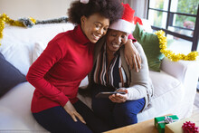Happy African American Senior Woman And Adult Daughter In Santa Hats Making Christmas Video Call