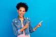 Photo of young cheerful afro american woman point finger empty space news amazed isolated on blue color background