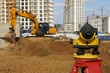 Photo of a level at the construction site of multi-storey buildings with a yellow excavator on the street in the city