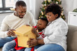 © Syda Productions - family, winter holidays and people concept - happy african american mother, father and baby son opening gift box at home on christmas
