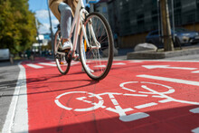 Traffic, City Transport And People Concept - Woman Cycling Along Red Bike Lane With Signs Of Bicycles On Street