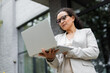 © LIGHTFIELD STUDIOS - low angle view of thoughtful african american businesswoman looking at laptop on city street