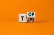 Top tips symbol. Turned a wooden cube with words 'Top tips'. Beautiful orange table, orange background. Top tips and business concept. Copy space.