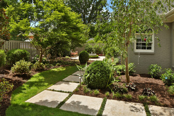 Stone path through backyard garden with bushes and trees