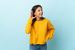 © luismolinero - Caucasian girl isolated on blue background listening to something by putting hand on the ear