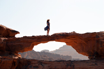 Poster - Beautiful view of the woman standing on a natural stone bridge. Wadi Rum, Jordan.