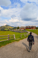 Poster - Vertical shot of the man walking along the rural road. Alpe di Siusi, Dolomites, Italy.