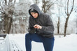 Man athlete using smartphone during winter workout in snowy city park