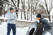 Man trainer and woman client during workout with a tire during cold winter and snowy day