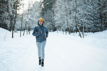 Wall Mural - Woman during her jogging workout during winter and snowy day