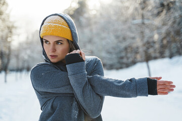 Wall Mural - Young athletic woman warming up before her winter workout