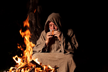 Medieval shepherd with flute by the campfire