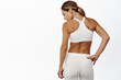Rear view of middle aged sports woman back, masculine and fit body, standing in activewear against white background